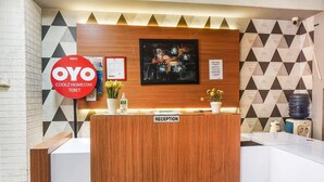 A reception desk with a 'Reception' sign, a framed abstract artwork, and a 'Coolz Homestay Tebet' sign.