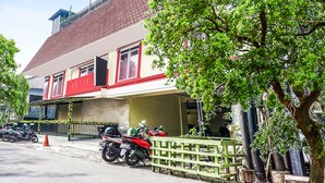 A building with a red and white facade, a balcony, and a tree in front.
