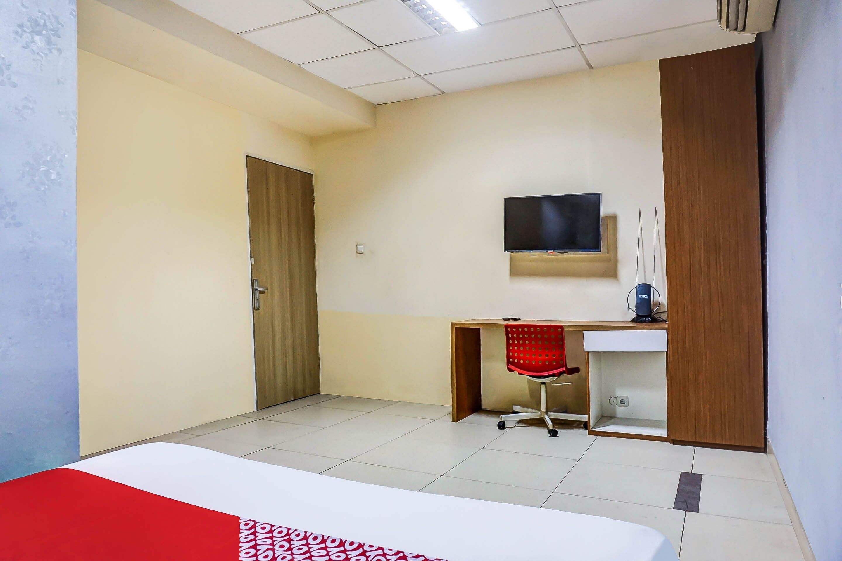 Une chambre d’hôtel comprenant un lit, un bureau, une chaise, une télévision et une armoire.