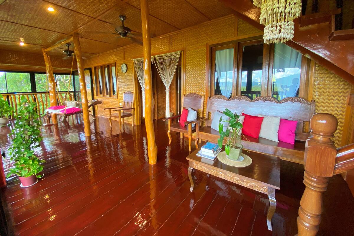 A wooden-floored room with a sofa, chairs, and a hanging chair.