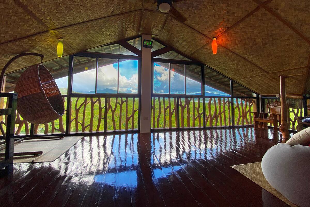 A room with a high ceiling, large windows, and a woven ceiling.