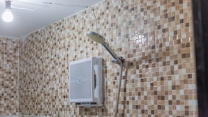 A bathroom with a tiled mosaic wall, a showerhead, and a wall-mounted air conditioning unit. - Salang Guest House (Penida Island)