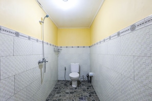 A small bathroom with a toilet, a shower, and tiled walls.