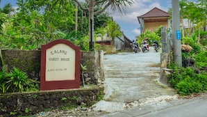 A guest house entrance with a sign, a paved pathway, and a building in the background. - Salang Guest House (Penida Island)