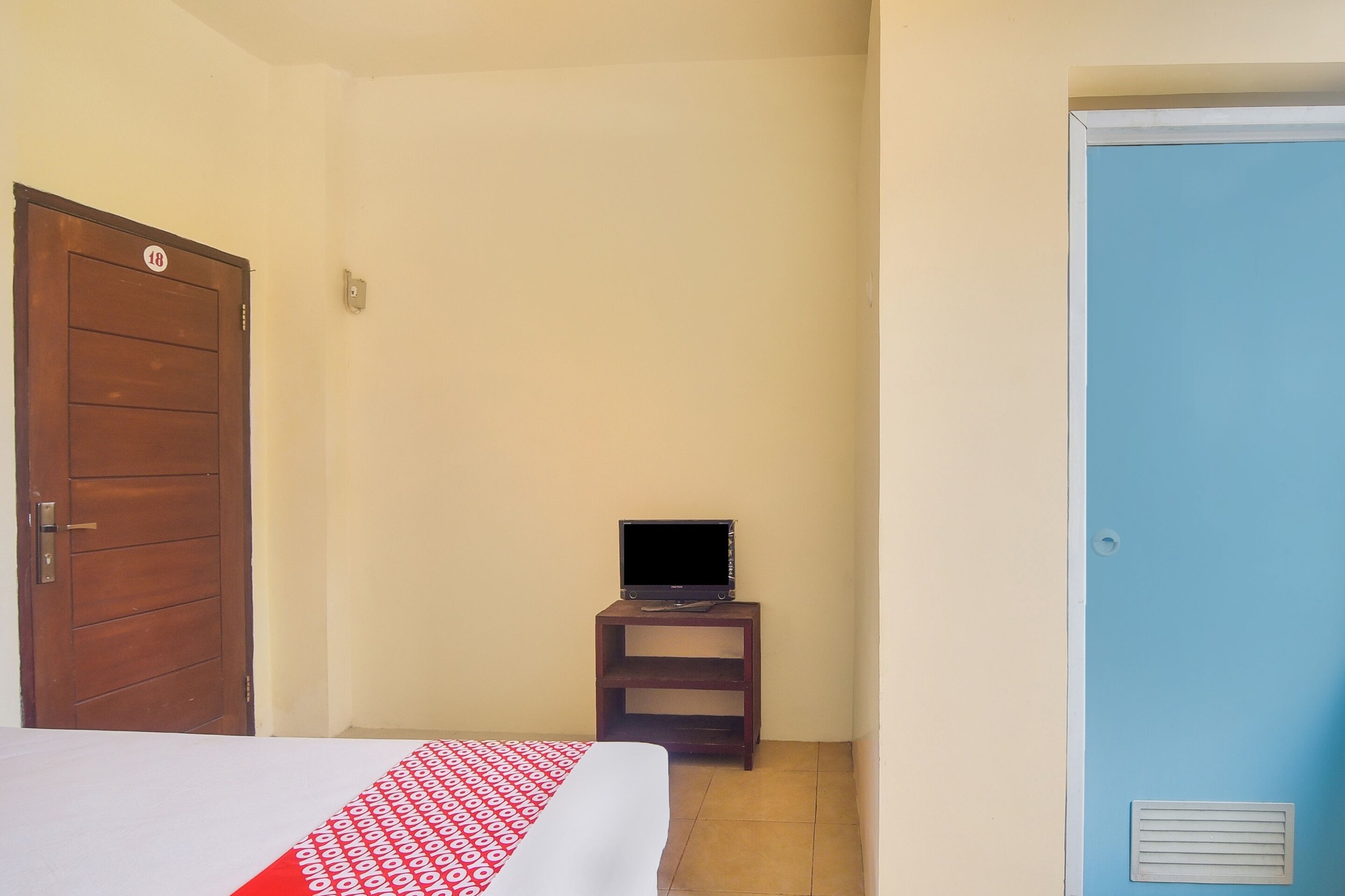 A room with a bed, a television on a small table, and a blue door.