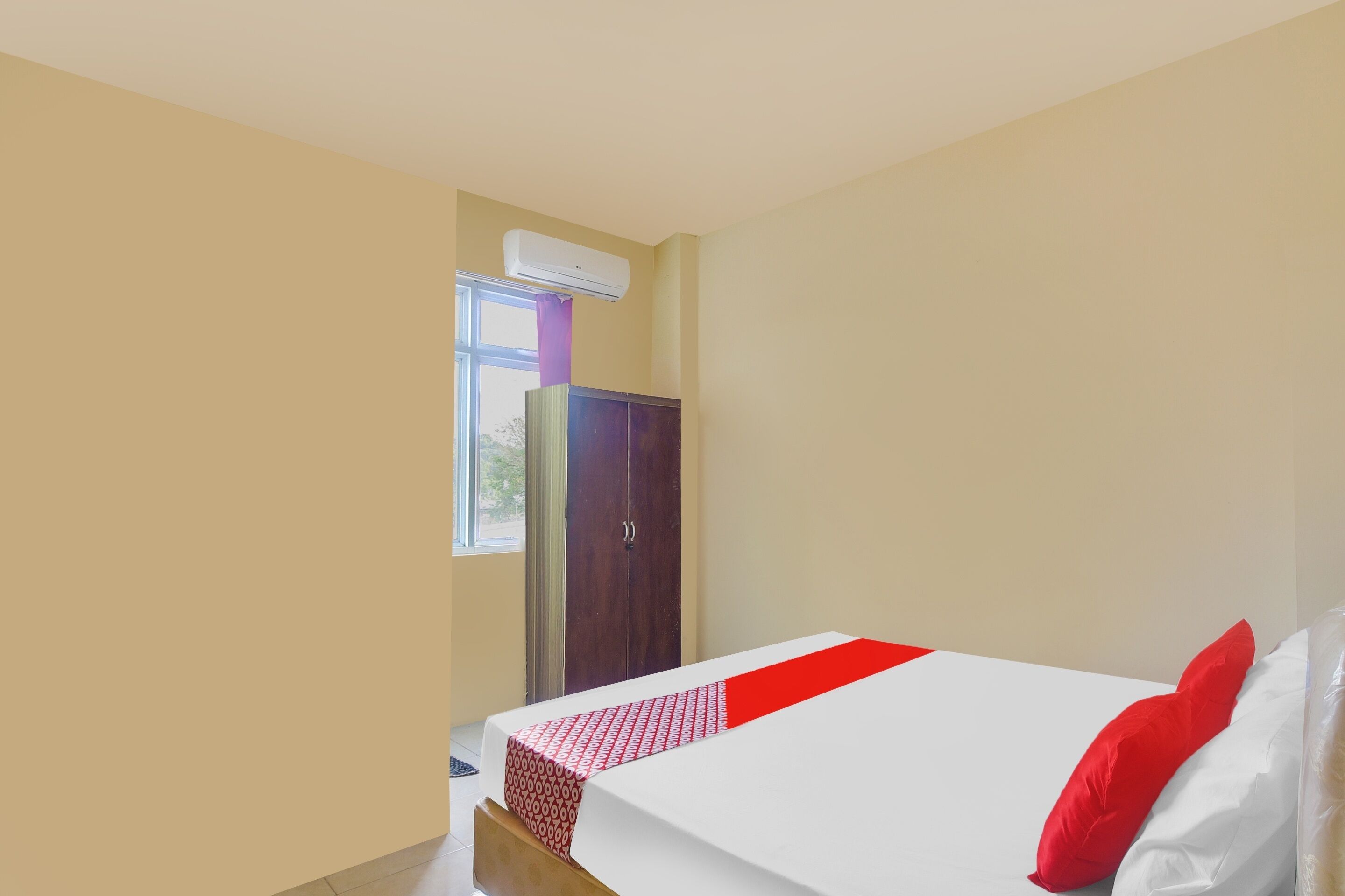 A hotel room with a bed, a wardrobe, and an air conditioning unit.