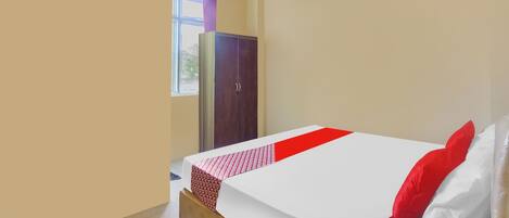 A hotel room with a bed, a wardrobe, and an air conditioning unit.