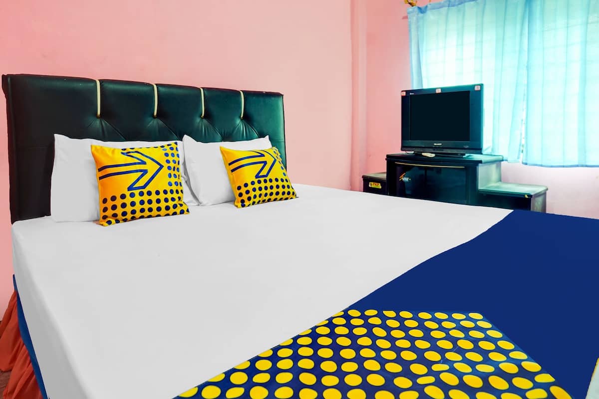 A bed with a white and blue bedspread, two pillows with yellow and black patterns, a black headboard, and a television on a stand beside the bed.