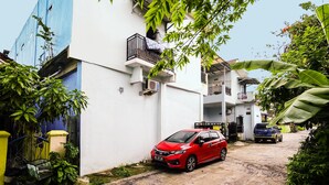 A residential area with a red car parked in front of a white building with balconies. - OYO Life 92046 Garuda Residence (Palembang)