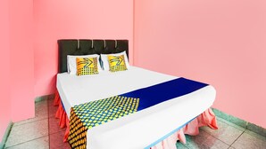A bed with a white and blue bedspread, two pillows with yellow and black patterns, and a pink wall. - OYO Life 92046 Garuda Residence (Palembang)