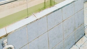 A bathroom with a rectangular bathtub, tiled walls, and a visible faucet. - OYO Life 92046 Garuda Residence (Palembang)