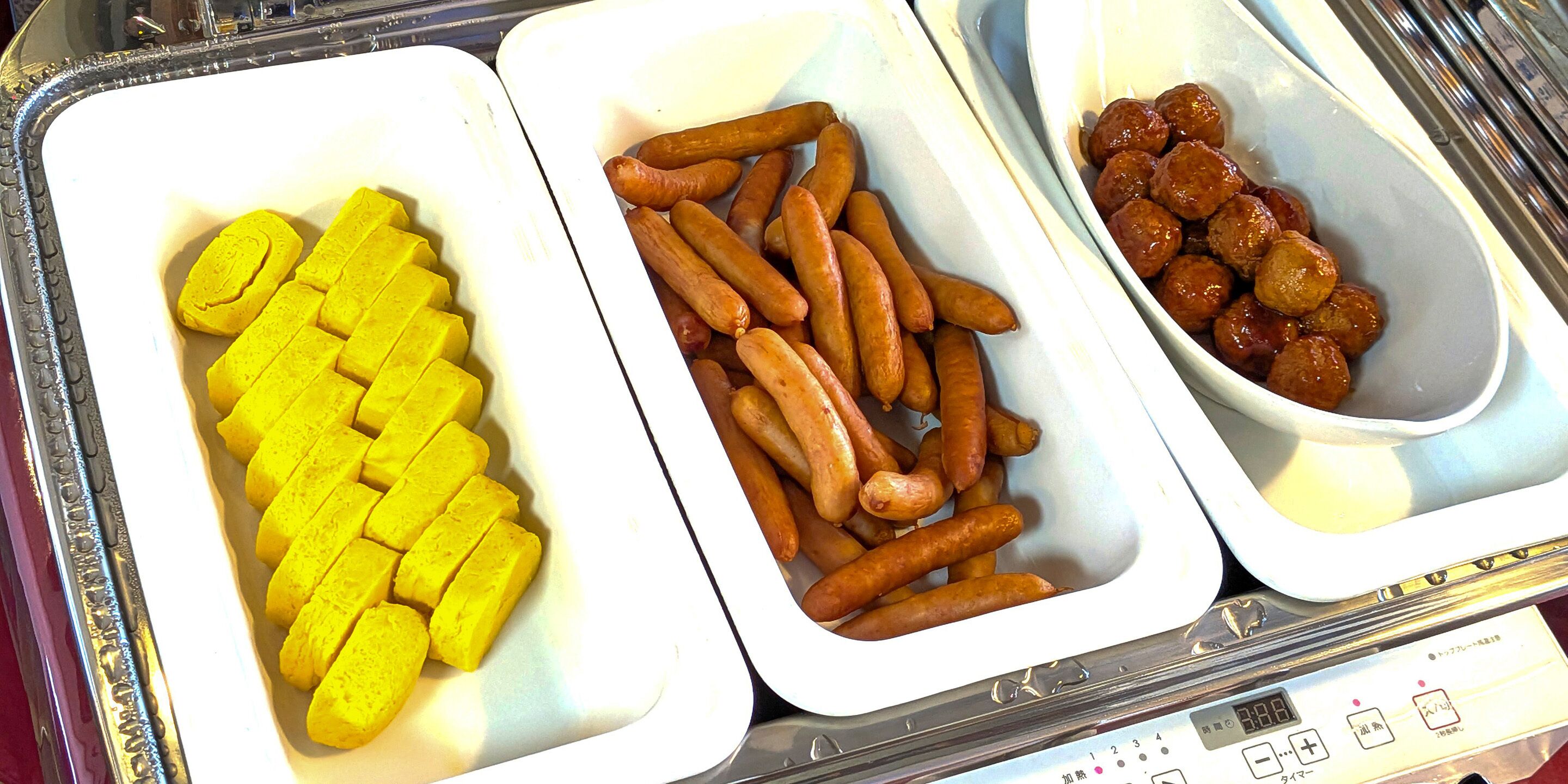 A buffet with three trays containing different food items.