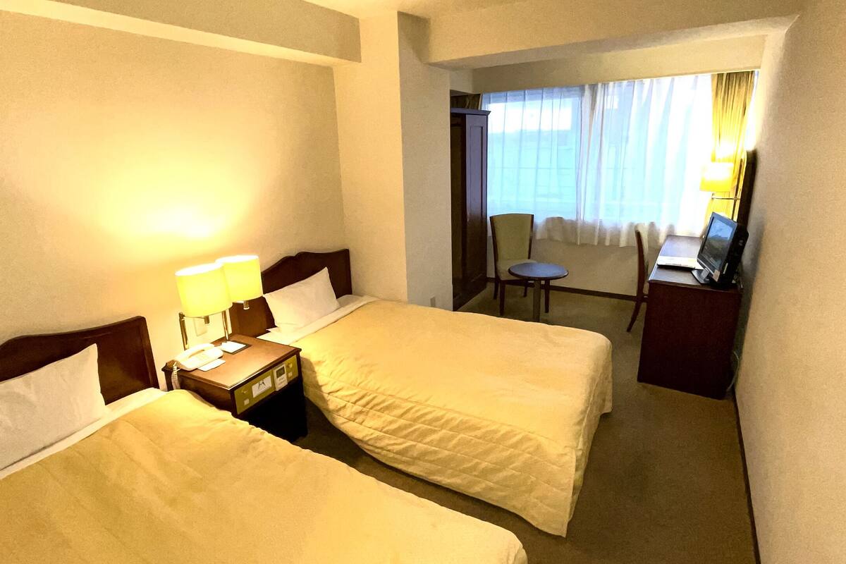 Habitación de hotel con dos camas, un escritorio y una silla.