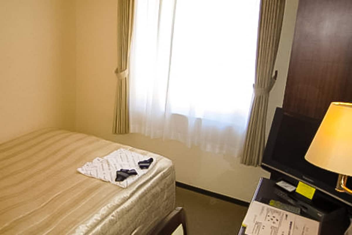 Una habitación de hotel con cama, televisión y lámpara.
