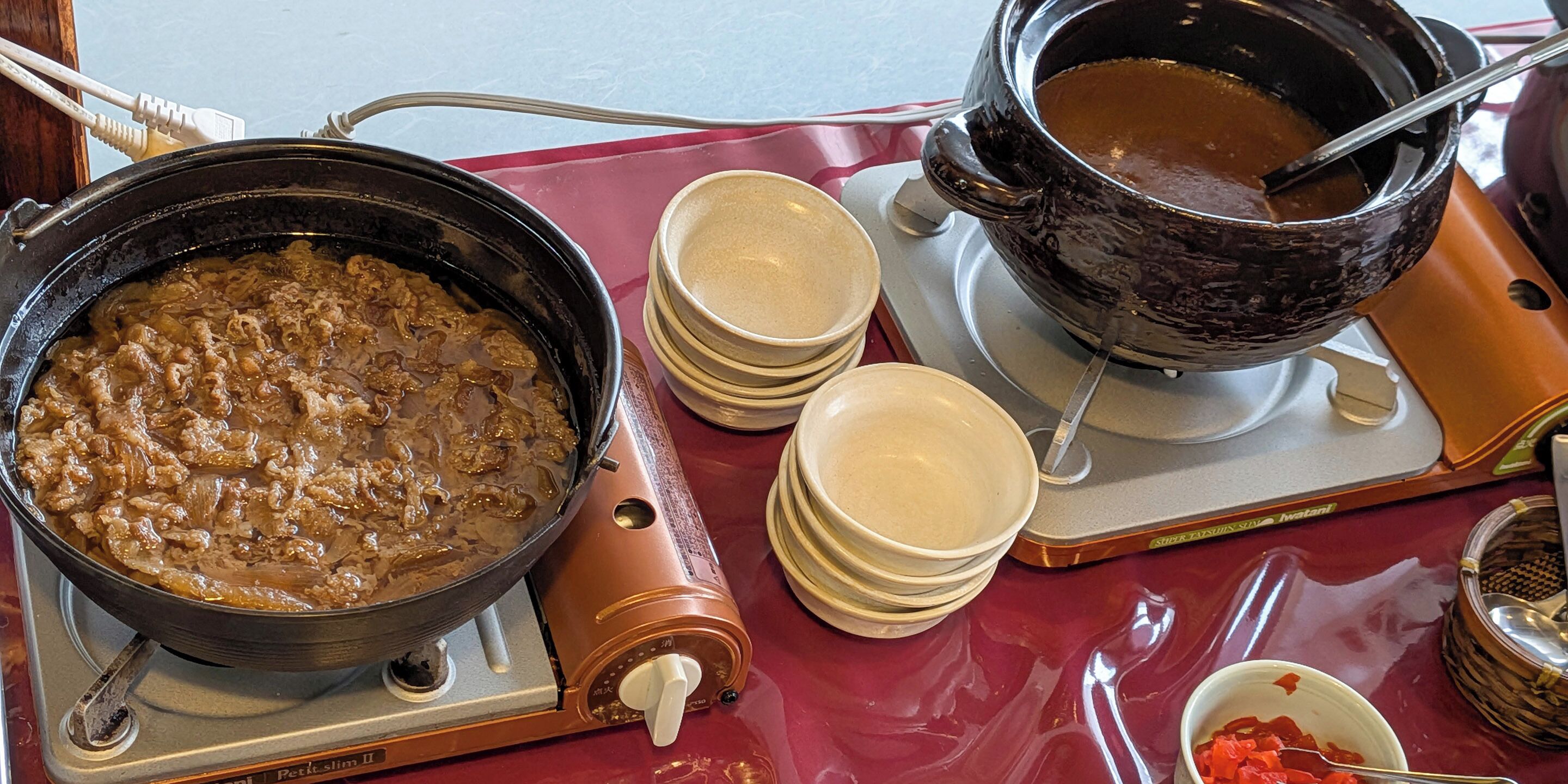 Uma bancada de cozinha com um pote de ensopado, uma tigela de sopa e tigelas empilhadas.