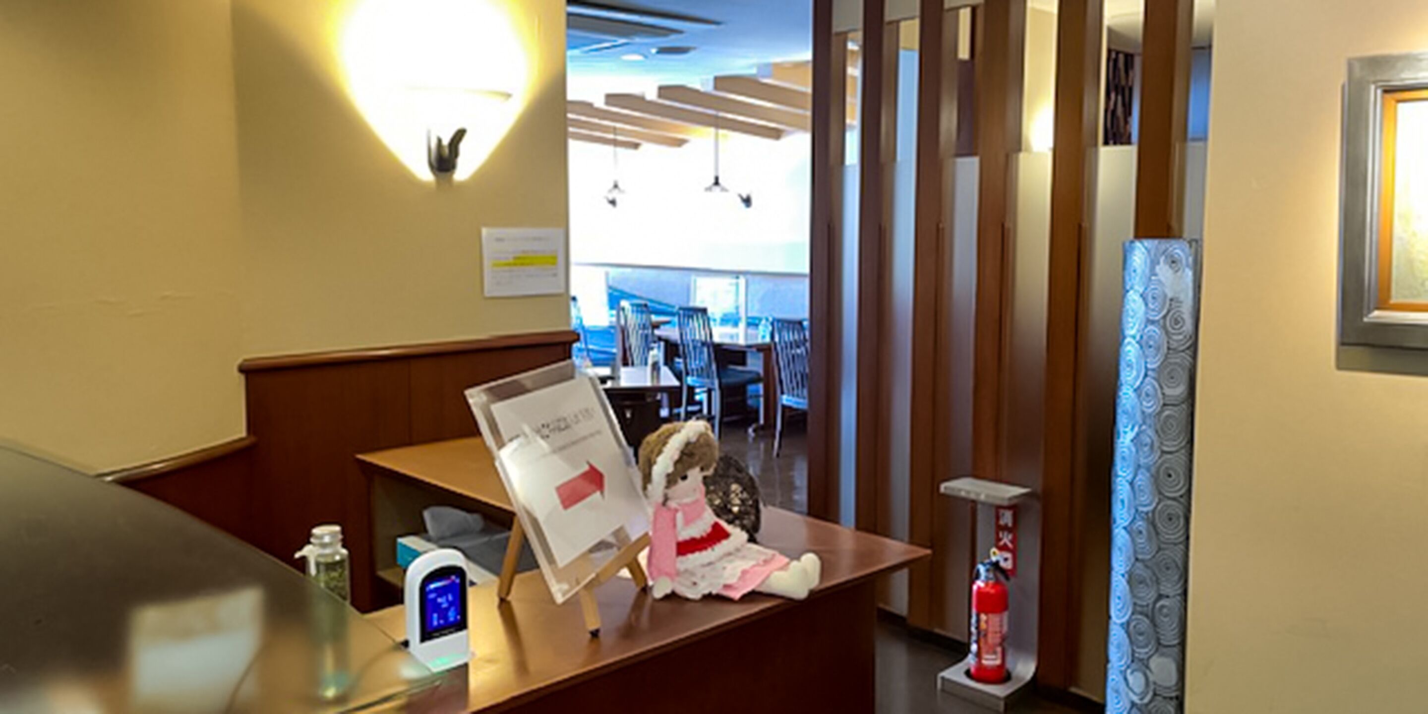 En receptionsdisk med et digitalt ur, en brandslukker og en pynteting.