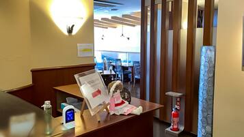A reception desk with a digital clock, a fire extinguisher, and a decorative item.