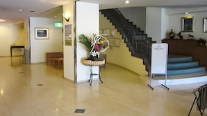 Vestíbulo de hotel con recepción, una escalera y una planta ornamental.