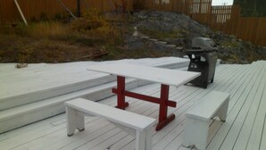 Una mesa de picnic con bancos en una terraza de madera.