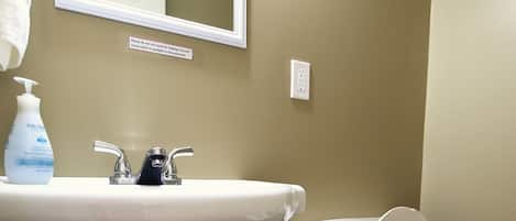 A bathroom with a white sink, a mirror, a toilet, and a white towel hanging on the wall.