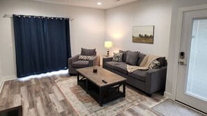Un salon avec un canapé, un fauteuil, une table basse et une lampe.