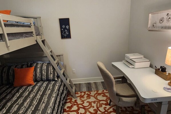 A compact room with a bunk bed, a desk with a printer, and a patterned rug. - New single level 3 bed 2 bath (Bel Aire)
