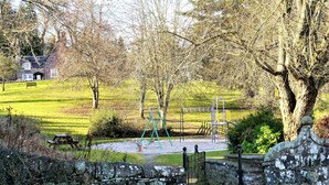 En park med legeplads, stenvæg og bænk.