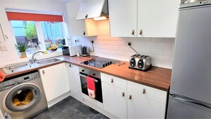 Et kompakt køkken med vaskemaskine, toaster og køleskab.