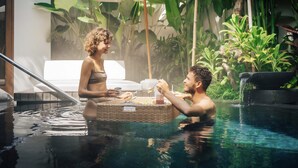 A couple in a pool with a wicker basket, surrounded by lush greenery and a white umbrella. - Uma Kalai (Ubud)