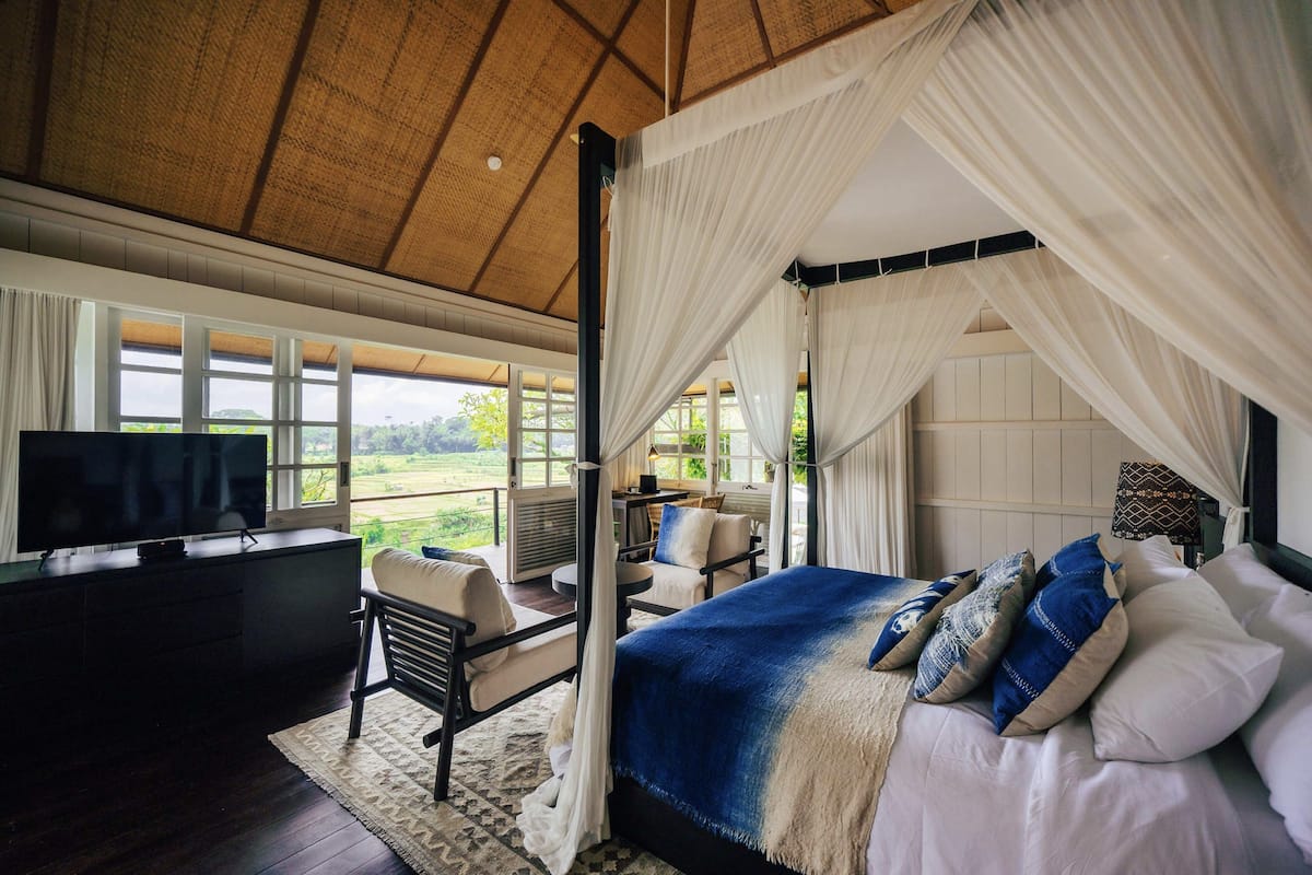 A bedroom with a large bed, a TV, and a view of the outdoors.