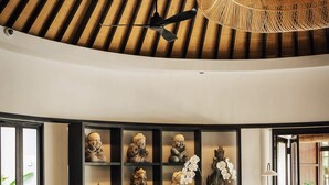 A modern living room with a curved ceiling, a sofa set, a coffee table, and decorative sculptures. - Uma Kalai (Ubud)
