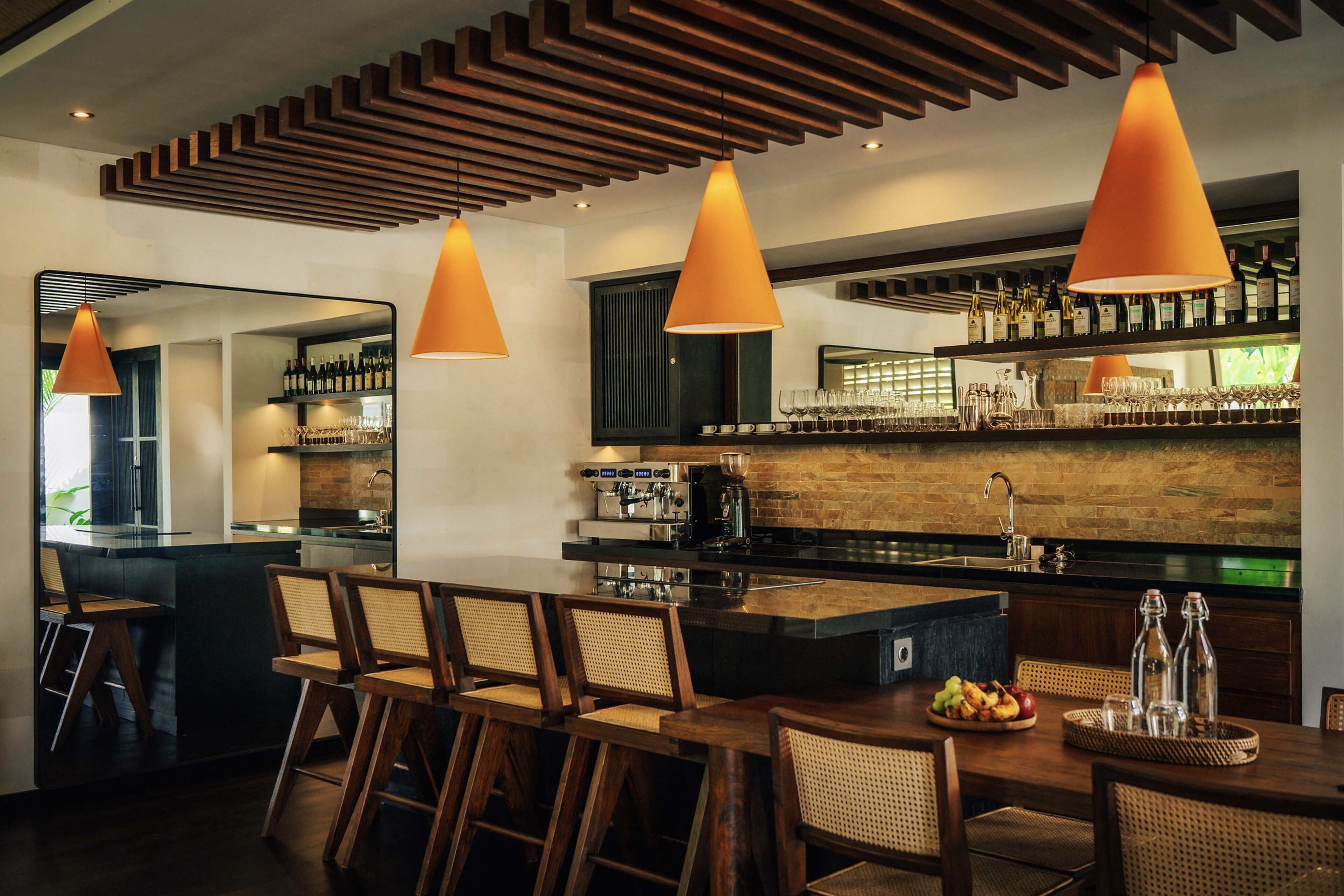 A modern kitchen with a bar area, wooden bar stools, and pendant lighting.