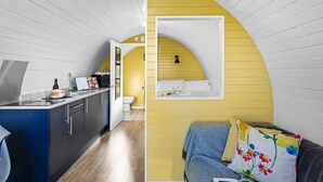 A compact living space with a kitchen area, a small bathroom, and a sleeping area with a sofa and a bed. - Honeycrisp Glamping Pod- Free Wi-F, Hot Tub (Wells)