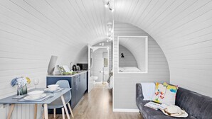 Un intérieur moderne comprenant un coin repas, une cuisine et un espace salon confortable avec un canapé et une fenêtre.