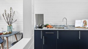 A modern kitchen with dark cabinets, a stainless steel sink, and a dining area with a table and chairs. - Bramley Glamping Pod- Free Wi-Fi, Hot Tub (Wells)