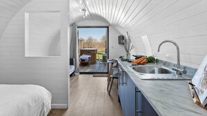 A compact kitchen with a sink, a dining area, and a view of the outdoors. - Bramley Glamping Pod- Free Wi-Fi, Hot Tub (Wells)