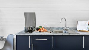 A modern kitchen with a stainless steel sink, a coffee maker, and fresh carrots on the counter. - Bramley Glamping Pod- Free Wi-Fi, Hot Tub (Wells)