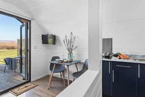 A compact kitchen with dark cabinets, a dining area with a table and chairs, and a sliding glass door leading to an outdoor patio.