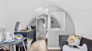 A compact, modern interior with a kitchen, dining area, and a cozy sleeping space. - Windsor Glamping Pod- Free Wi-Fi, Hot Tub (Wells)