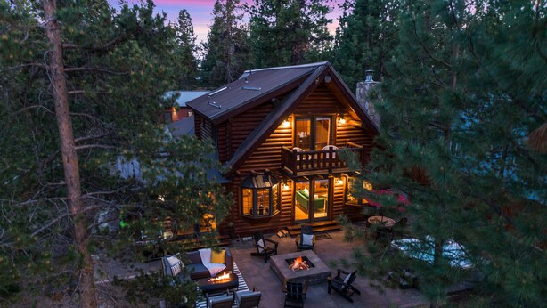 A log cabin with a deck, outdoor seating, and a fire pit.