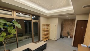 A reception area with a seating bench, a wooden bookshelf, a door marked "Toilet," and a potted plant. - Serorin Light Hotel Tokyo (Tokyo)