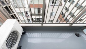 A rooftop terrace with a white air conditioning unit and a metal railing. - Serorin Light Hotel Tokyo (Tokyo)
