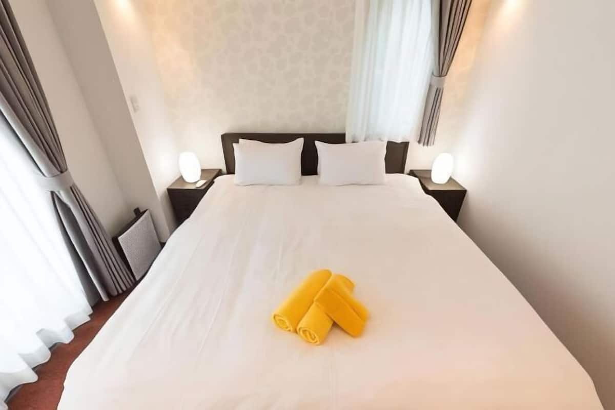 A hotel room with a large bed, two bedside tables with lamps, and a curtain on the window.