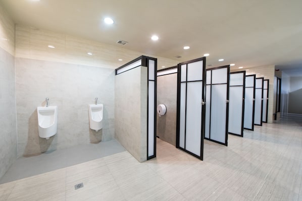 A modern restroom with multiple urinals and privacy partitions. - PassGo Digital Airport Hotel Bali (Tuban)