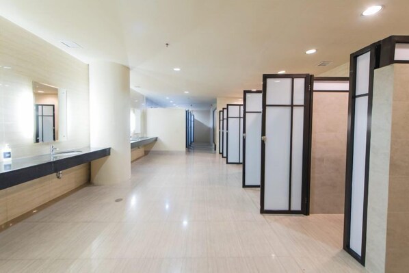 A modern hotel corridor with a long reception desk, a series of private rooms, and a clean, tiled floor.