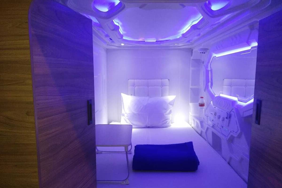 A room with a bed, a chair, and a control panel.