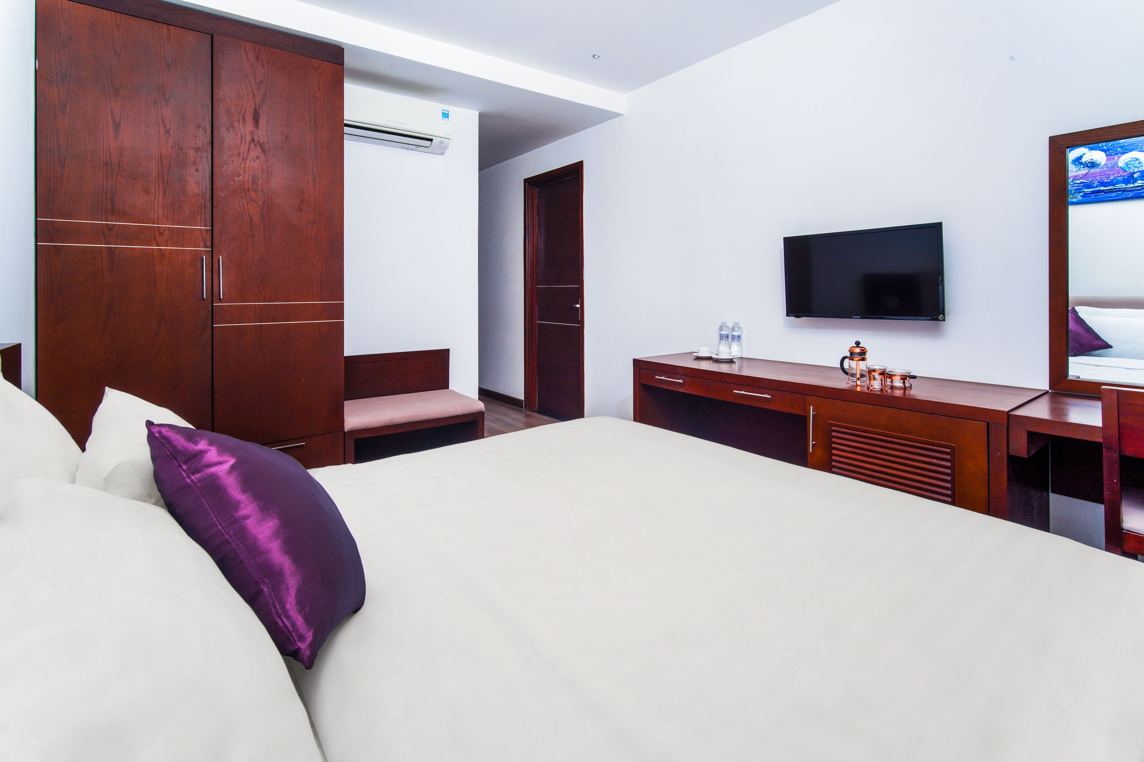 A hotel room with a bed, a desk, a television, and a wardrobe.