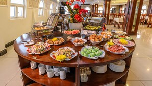 Buffet com diversos pratos e um arranjo floral.