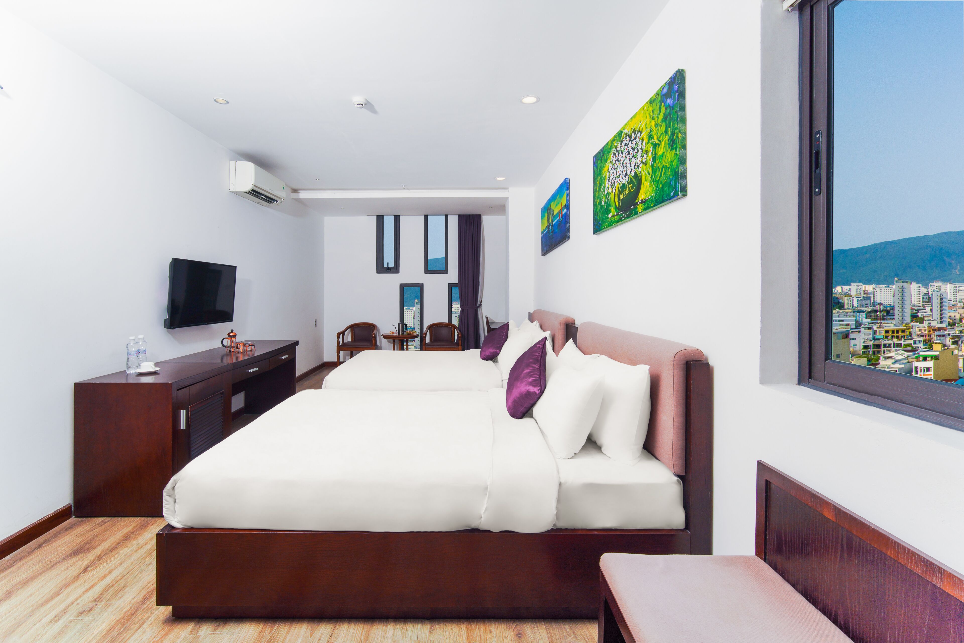 A modern hotel room with a large bed, a desk, a chair, and a TV.