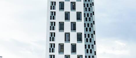A tall hotel with a modern design, featuring a prominent entrance and a visible restaurant named "CARDI PIZZERIA" at the ground level.